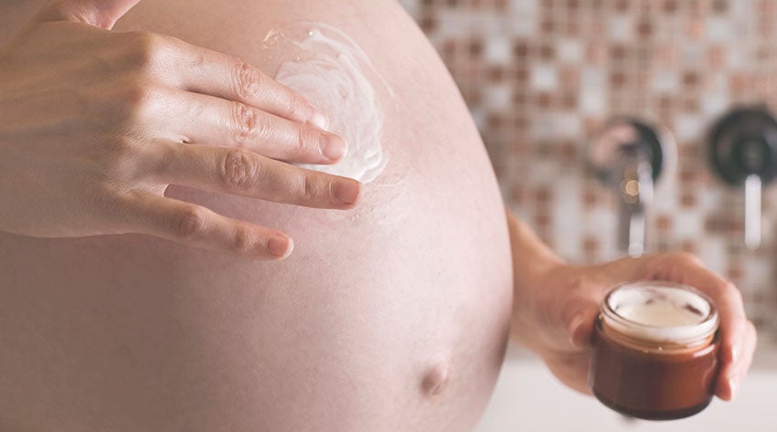 Pregnant mother rubbing cream on her baby bump
