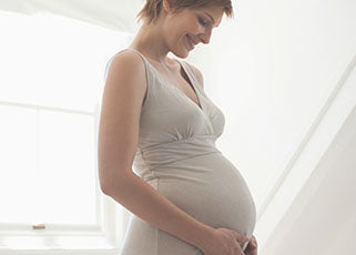 Pregnant mother smiling while looking down at her baby bump