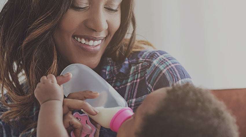 Mother feeding baby with bottle of expressed milk