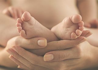 mother holding newborn baby feet