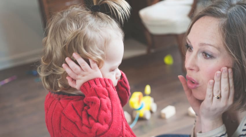 Toddler with her hands covering her ears