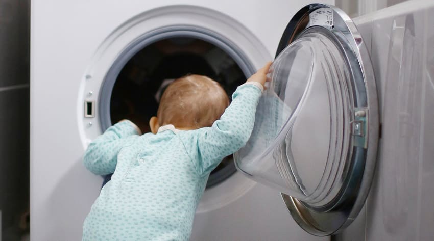 Toddler peering into an open washing machine