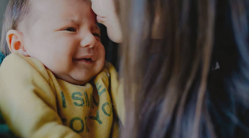 Woman kissing newborn baby on the forehead