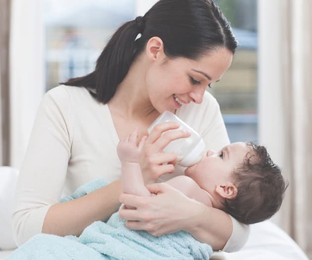 Woman bottle feeding a baby in her arms