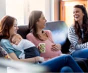 Three mothers chatting and laughing on a sofa