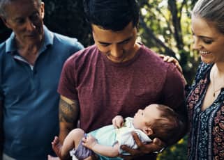 Dad holding newborn surrounded by family