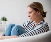Woman sat on the sofa looking depressed