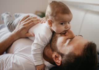 Dad laying down and kissing a baby