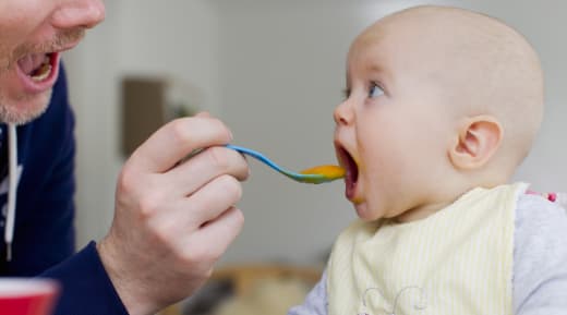 father feeding a baby puree food