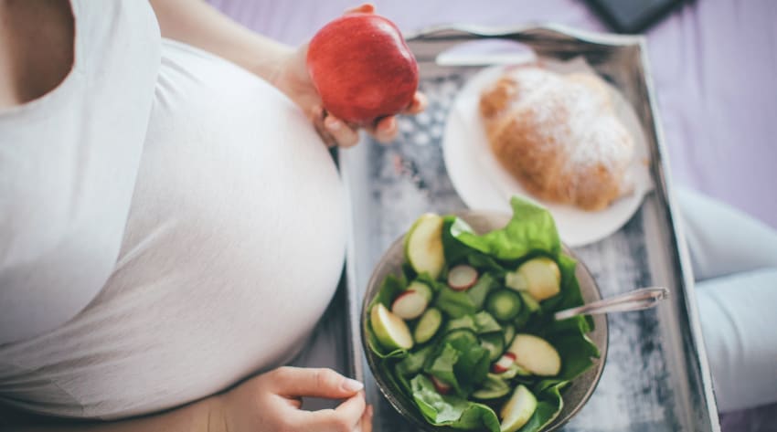 pregnant-women-holding-apple-and-tray-of-food