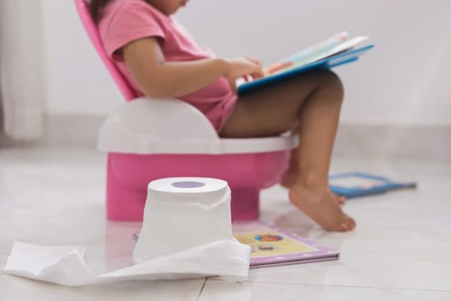 Baby on a training potty while reading a book