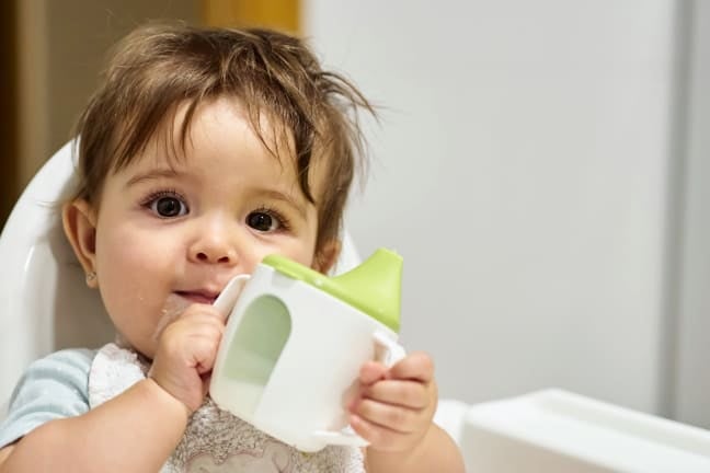 A child holding a beaker full of milk