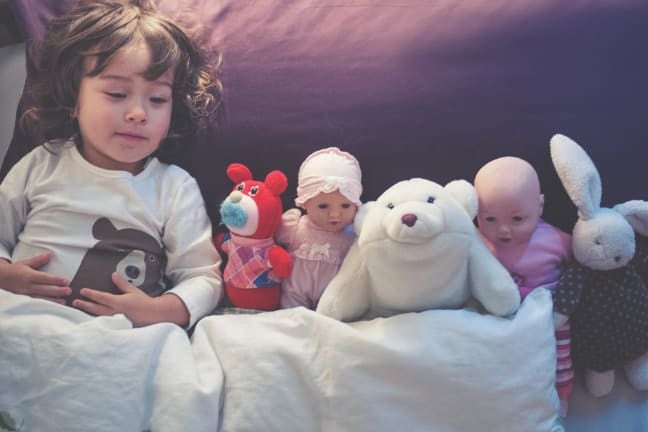 A child sharing their bed with their toys