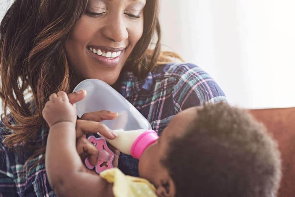 Person holding and bottle-feeding a baby while sitting indoors