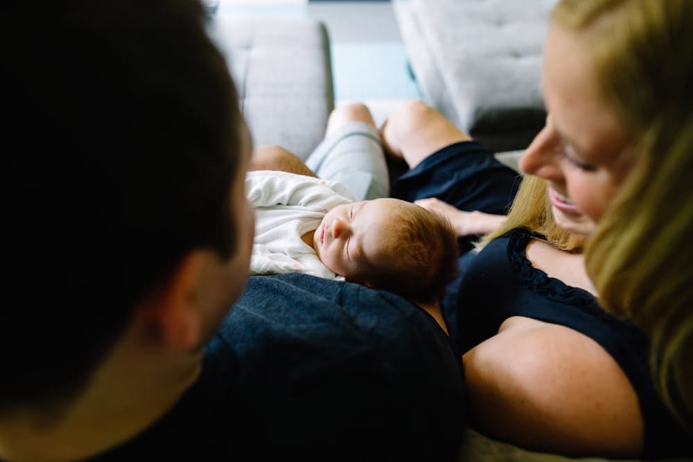 Newborn resting in a caregiver’s arms while parents seek information and support on infant digestive health