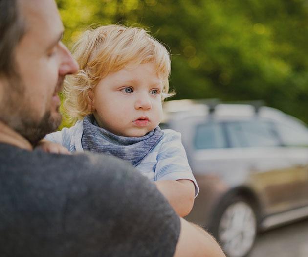 A parent holding their toddler before getting in a car