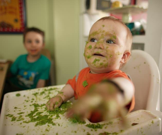 Messy baby eating on a baby chair