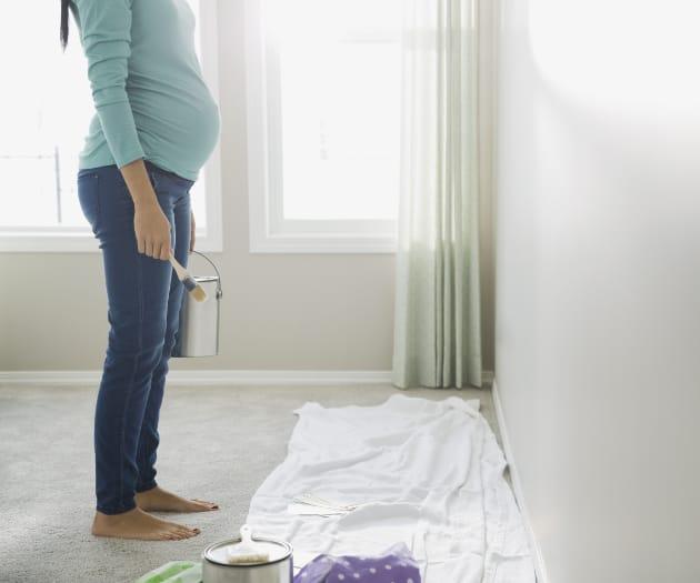 Pregnant mother holding a paint brush and a pot of paint