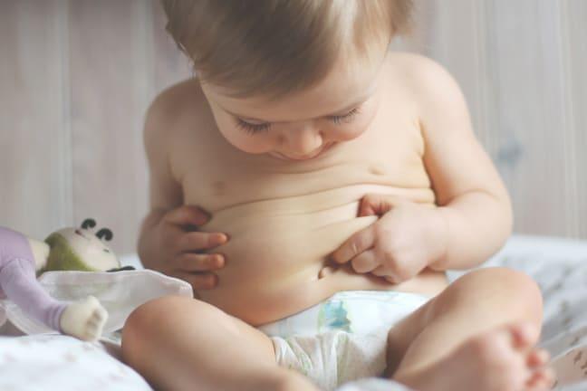 Toddler playfully pointing at his tummy, representing the importance of healthy gut development and immunity in young childre