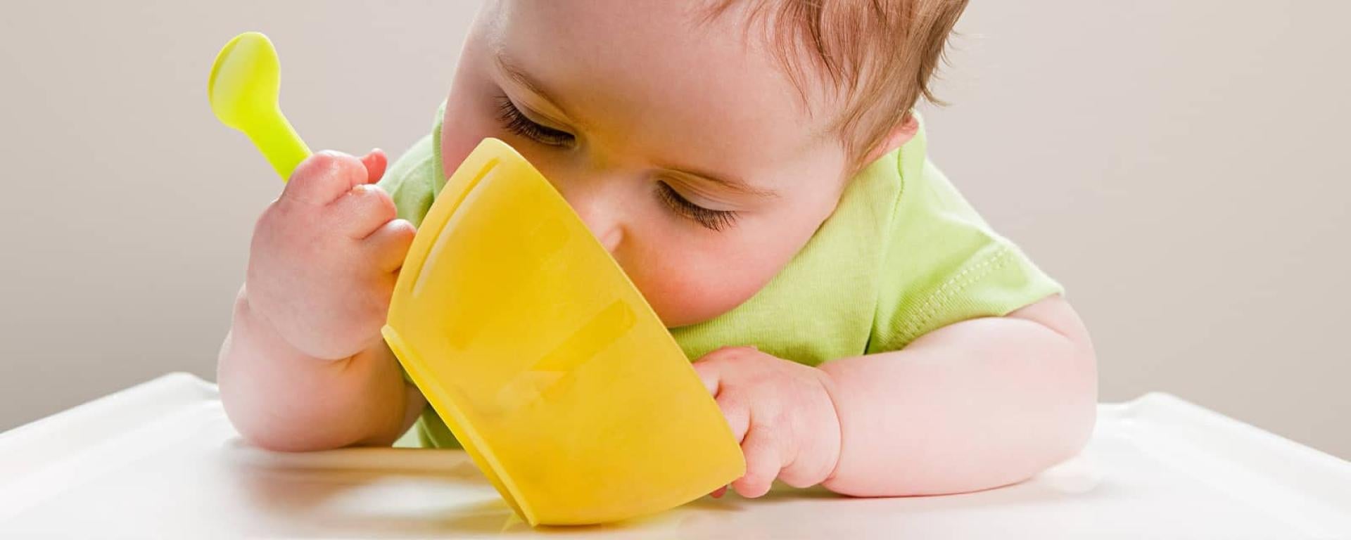 Baby using bowl and spoon